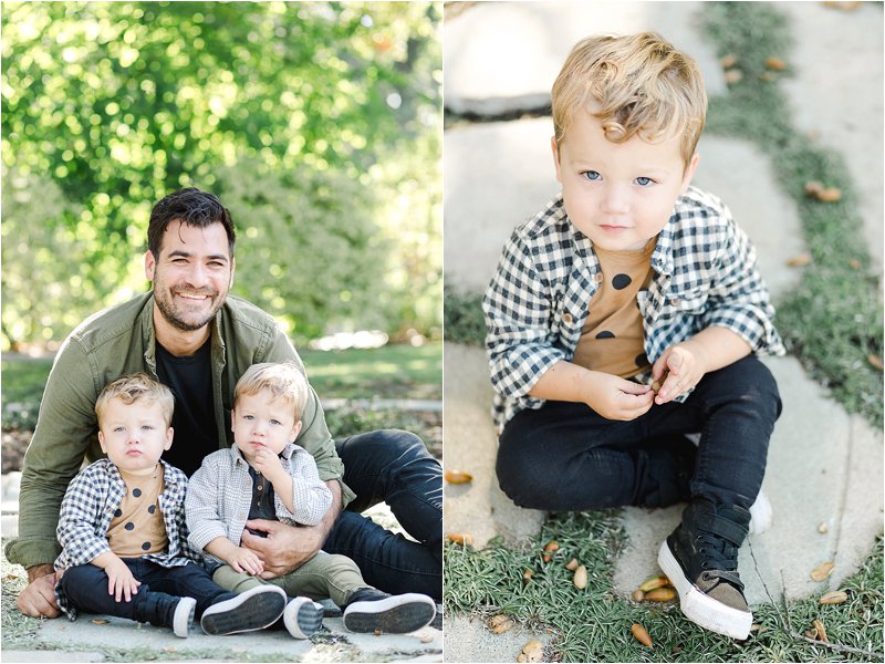 Image on the left shows father sitting on the ground with his 1 year old twin sons.  Father is wearing black jeans and a black t-shirt with an opened olive green button down layered on top.  Twin on the left is wearing a brown t-shirt with brown polka dots with a black and white checkered button down layered on top.  Paired with black jeans and black high top sneakers.  Twin on the right is wearing a black t-shirt with a cream and taupe flannel shirt layered on top.  Paired with olive green pants and black high top sneakers.  This image shows an excellent example of fall family photo outfits.