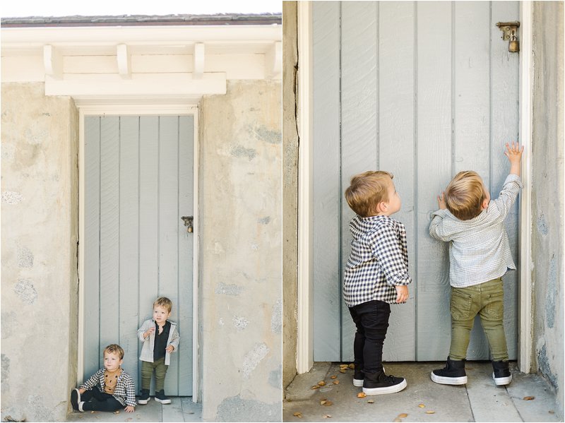 2 year old twin brothers play in front of grey-blue door during their fall family photo session in Pasadena, CA.