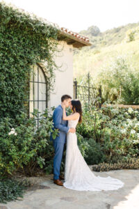 Brunette bride in lace, v-neck, tank gown, and brunette groom in blue suit, rest their foreheads together while taking wedding photos at Klenter Ranch in Carpenteria, CA.