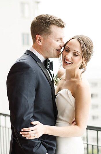 Groom kisses his bride on the cheek as they embrace