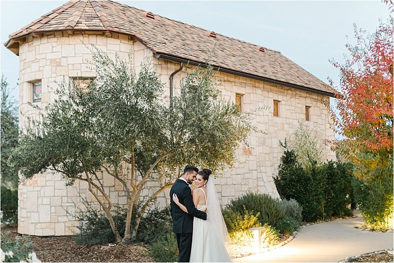Bride and groom smile as they snuggle into each other following their Italian villa wedding.  The decided to maximize the season and the aesthetic of the venue when deciding how to choose the perfect wedding color scheme and chose fall colors