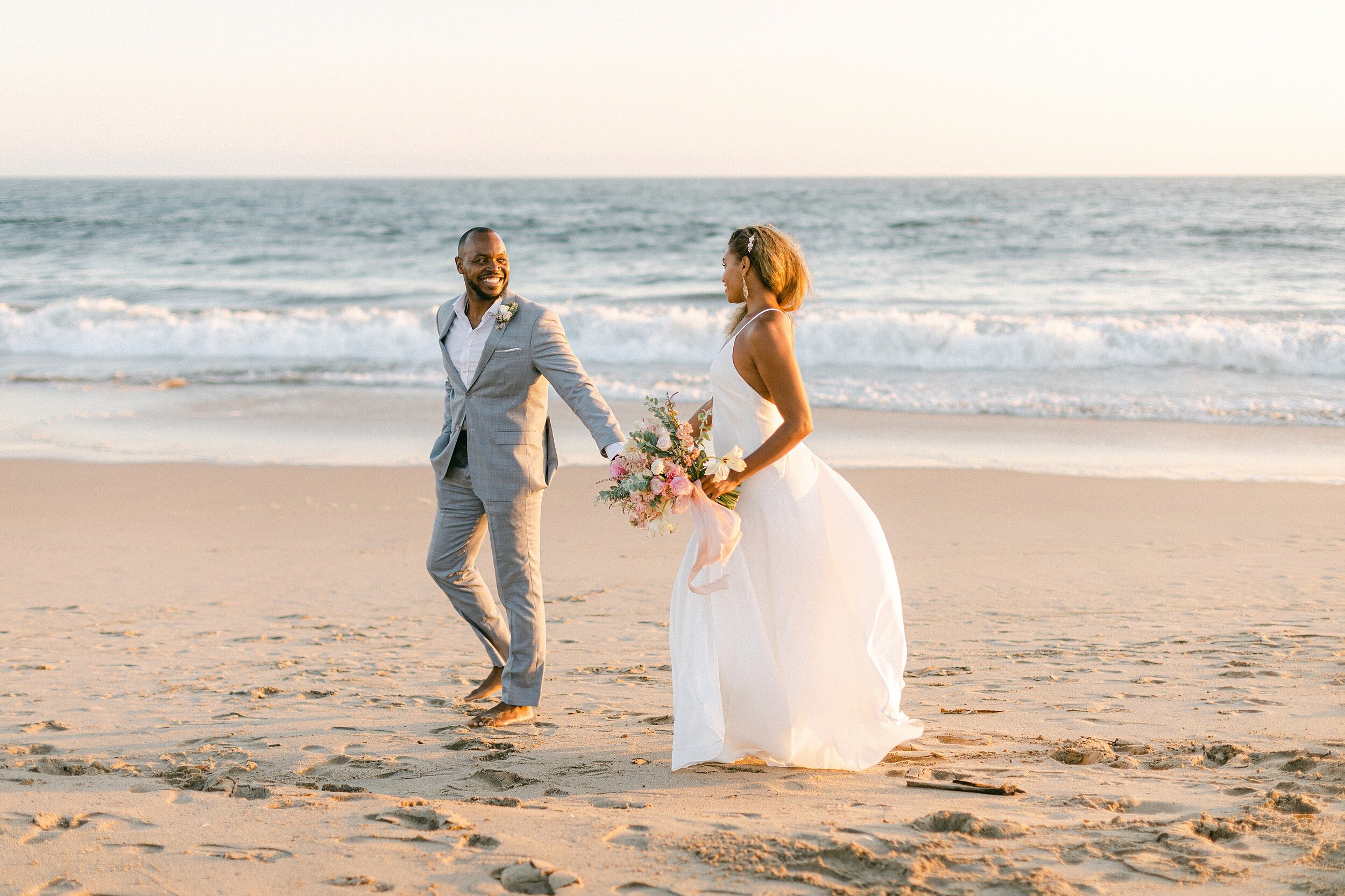 Bride and groom of color hold hands and take a walk along the beach following their intimate springtime elopement in Marina Del Rey, CA.