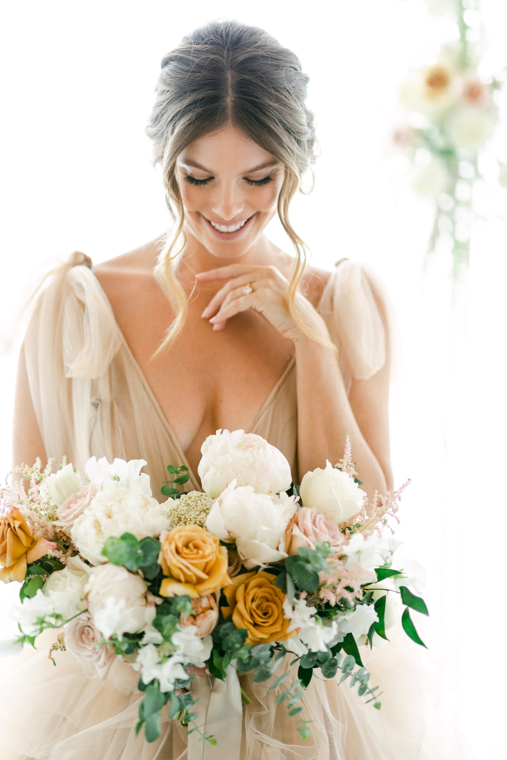 Blonde bride holding a neutral bouquet with white and tan flowers