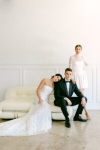 Groom wearing black tux poses with 2 brides during an editorial wedding photo shoot in downtown Los Angeles Studio.