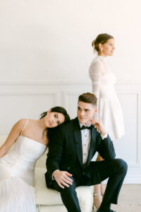 Groom wearing black tux poses with 2 brides during an editorial wedding photo shoot in downtown Los Angeles Studio.