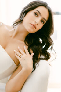 Romantic bridal portrait of bride with dark brown hair with hand on chest showcasing her engagement ring.