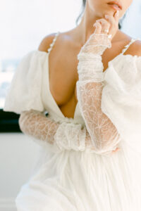 Cropped detail shot of bride wearing flowy lace and chiffon gown with deep v neckline.