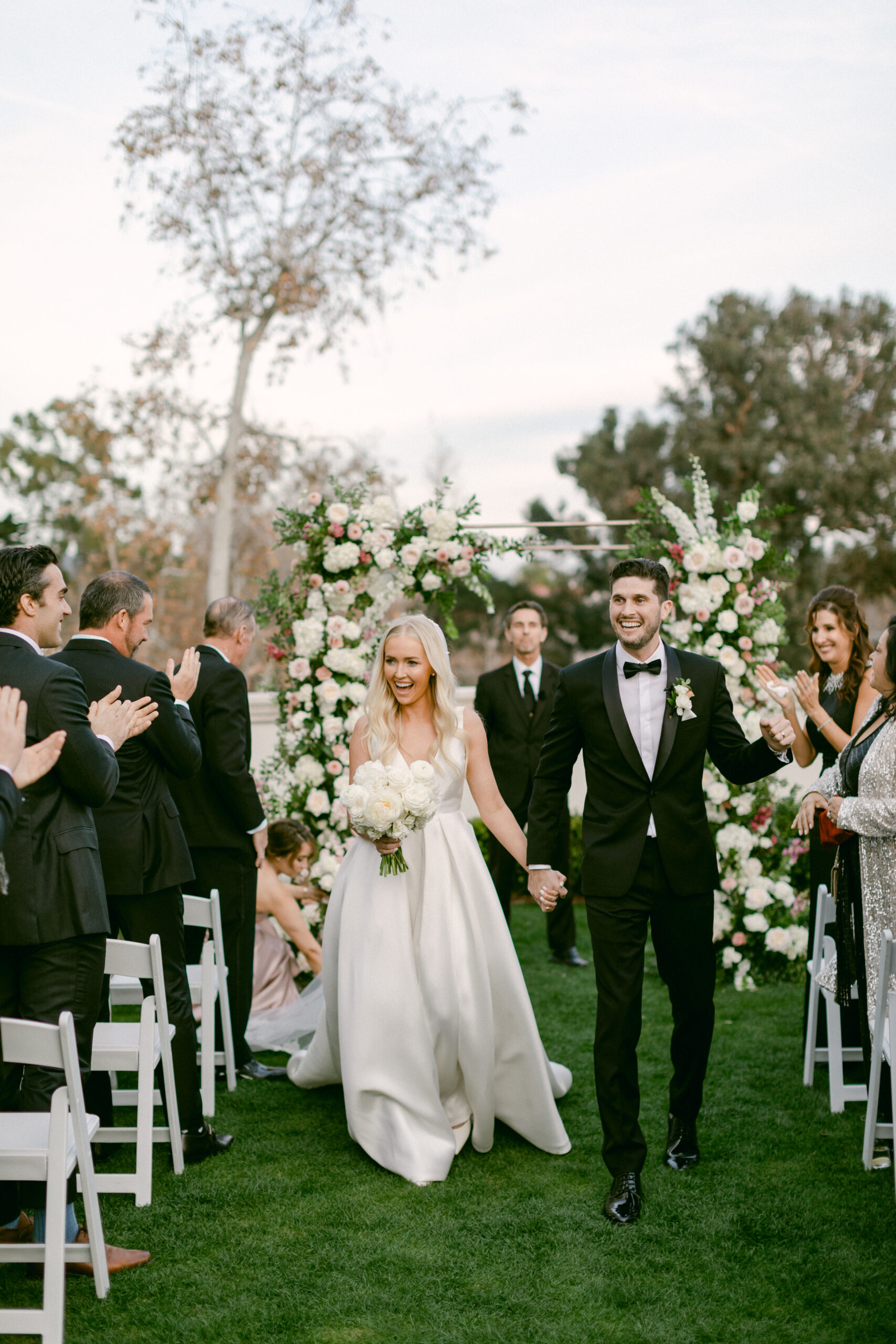 Bride and Groom excitedly exit their wedding ceremony after just being married at Rosewood Miramar in Montecito, CA.
