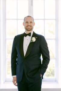 Portrait of a groom facing toward the camera with one hand in his pocket.