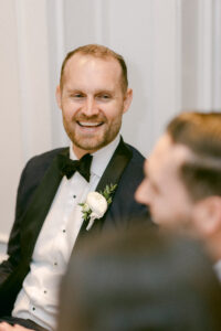 Groom laughs during reception during toasts.
