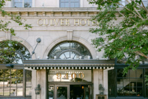 Detail photo of the Culver Hotel entrance, showcasing the art deco awning framed by trees.