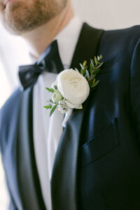 Detail photo of groom's white ranunculas boutonniere