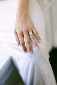 Candid detail photo of bride's ring as she rests her hand on her leg.