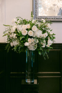 Detail photo of a tall white floral arrangement on pedestal at the ceremony site.