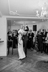Black and white photo of groom twirling bride during their first dance as husband and wife.