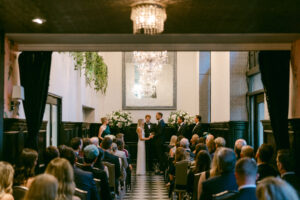 Photo of bride and groom holding hands and exchanging vows during their intimate micro wedding at the Culver Hotel.