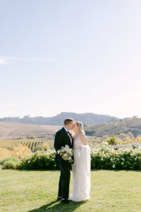 Bride and groom share a kiss on a hillside overlooking the San Luis Obispo vineyards at Greengate Ranch.