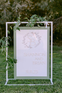 Custom white and sage green welcome sign with the bride and groom's monogram, names and wedding date.