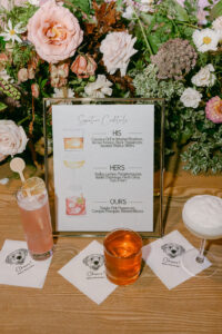 Detail photo featuring the signature cocktail sign and all three signature cocktails along with the custom napkins showcasing the bride and groom's dog.