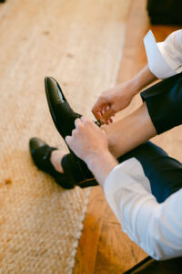 Detail photo of groom tying his shoe while getting ready for his wedding.