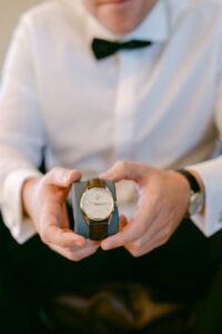 Detail photo of groom holding the new watch his bride gave him as a wedding gift.