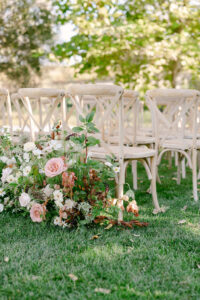 Detail photo showing the crossback chairs and the floral floor display at the lakeside ceremony site.