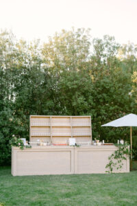 Detail photo of a beautiful light wood bar with a white umbrella to the right and greenery cascading down the right side of the bar.