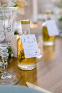 Detail photo of custom mini olive oil bottles which served as guest favors and their seating assignements.