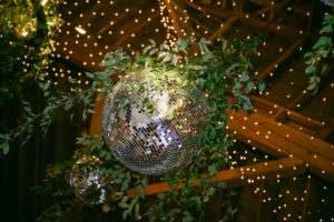 The party vibe tone was set inside the barn with multiple mirrored disco balls hanging over the dance floor along with twinkle lights and Italian ruscus greenery.  