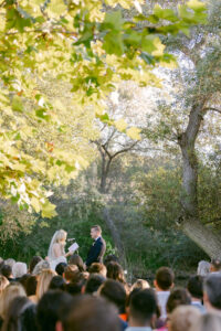 Bride reads her vows to her (almost) new husband during their wedding ceremony as their guests look on.