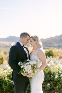 Bride and groom both hold the bridal bouquet as they rest their foreheads together following their first look at Greengate Ranch in San Luis Obispo.