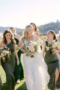 Candid walking photo of blonde bride surrounded by her bridesmaids in green dresses 