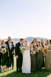 Bride and groom share a kiss as their bridal party surrounds them as they prepare for their wedding ceremony at Greengate Ranch