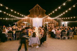 Nighttime motionblur shot of the outdoor reception featuring the hanging market lights as the guests enjoy their meal.