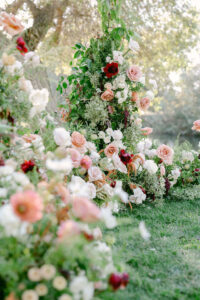 Floral detail photo showcasing the stunning ceremony floral install by Unique Floral Designs featuring white, pink, peach and maroon florals.