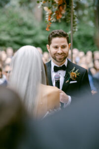 Groom smiles as he shares his vows with his wife to be.