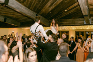 Bride and groom smile at each other from their chairs during the horah.