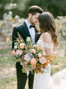 Bride and groom embrace and share an sweet moment prior to their wedding ceremony. Bride is holding her beautiful fall colored bouquet as they rest their foreheads together.