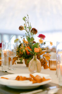 Fall toned florals in mini, fluted glass vases with votives graced the reception tables.