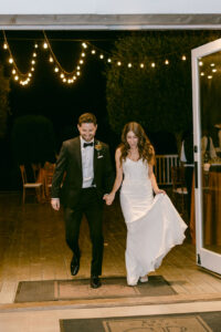 Bride and groom hold hands during their grand entrance into their wedding reception.