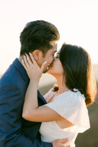 Bride to be pulls her fiance's face to hers as they share a kiss following their proposal.