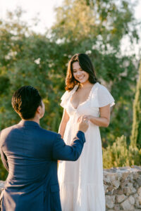 Groom to be places a beautiful emerald cut engagement ring on his fiance's finger during their Malibu proposal.