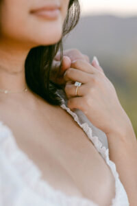 Detail photo showcasing Amy's emerald cut engagement ring as she holds her fiance's hand.