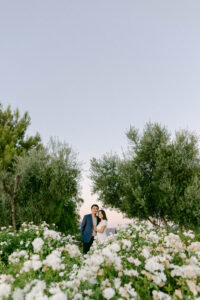 Bride and groom to be are framed by the olive trees and white roses at Stonewall Ranch Malibu, following Tyler successfully planning the perfect proposal.