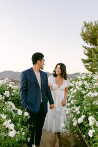 Newly engaged couple holds hands and walk through the white rose garden at Stonewall Ranch in Malibu following the perfect proposal.