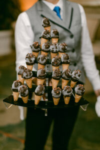 Server holds a pyramid of mini ice cream cones.