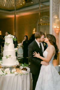 Bride and groom share a kiss after cutting their wedding cake at their Four Seasons of Beverly Hills wedding reception.