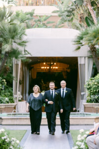 Groom being escorted down the aisle by his parents during his wedding ceremony in the courtyard of the Four Seasons Beverly Hills.