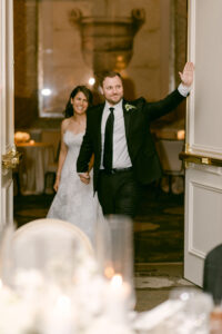 Groom waves as he leads his bride into their wedding reception during their grand entrance into the ballroom at the Four Seasons Beverly Hills.