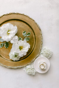 Wedding flatlay of wedding rings surrounded by white flowers. Styled and photographed by SoCal wedding photographer Tiffany J Photography.